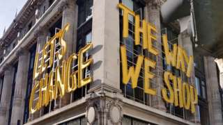 "Let's Change the way we shop" yellow sign onside of Selfridges building