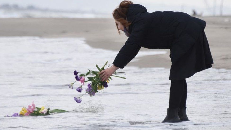 A woman puts flowers into the sea to pray for victims of the 2011 earthquake and tsunami in Sendai, northern Japan on March 11, 2016