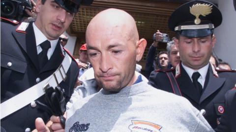 Marco Pantani is led out of a hotel after failing a blood test at the 1999 Giro d'Italia