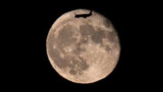 A passenger plane flying over the full moon before landing at San Francisco International Airport is photographed from Burlingame in California, United States on August 2, 2023.