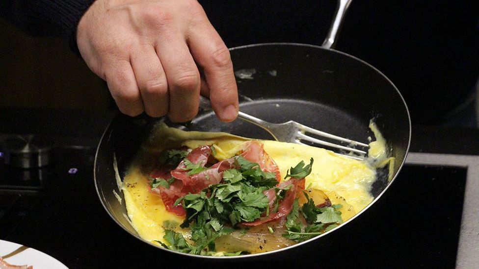After adding charcuterie and coriander, the omelette is rolled (Credit: Emily Monaco)