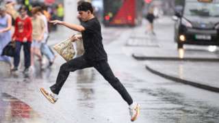 Man with bag jumps over puddle